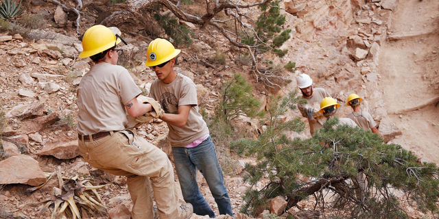 Crew members hand off boulders